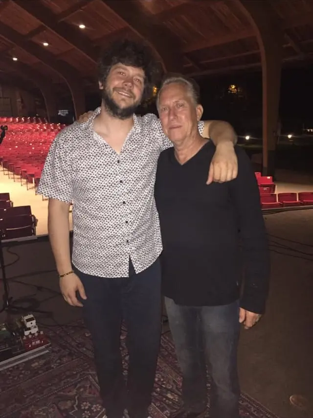Johnny with his arm around a friend in an empty theater