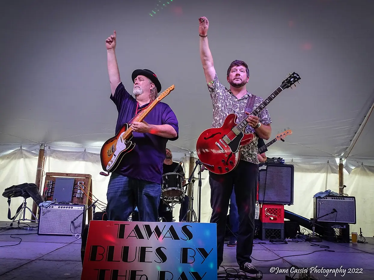 Johnny and another guitarist raising their fists onstage at a festival tent