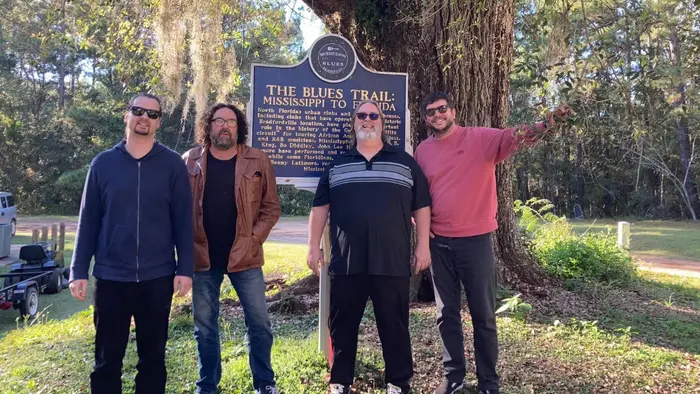 Johnny and bandmates beside a Mississippi Blues Trail marker