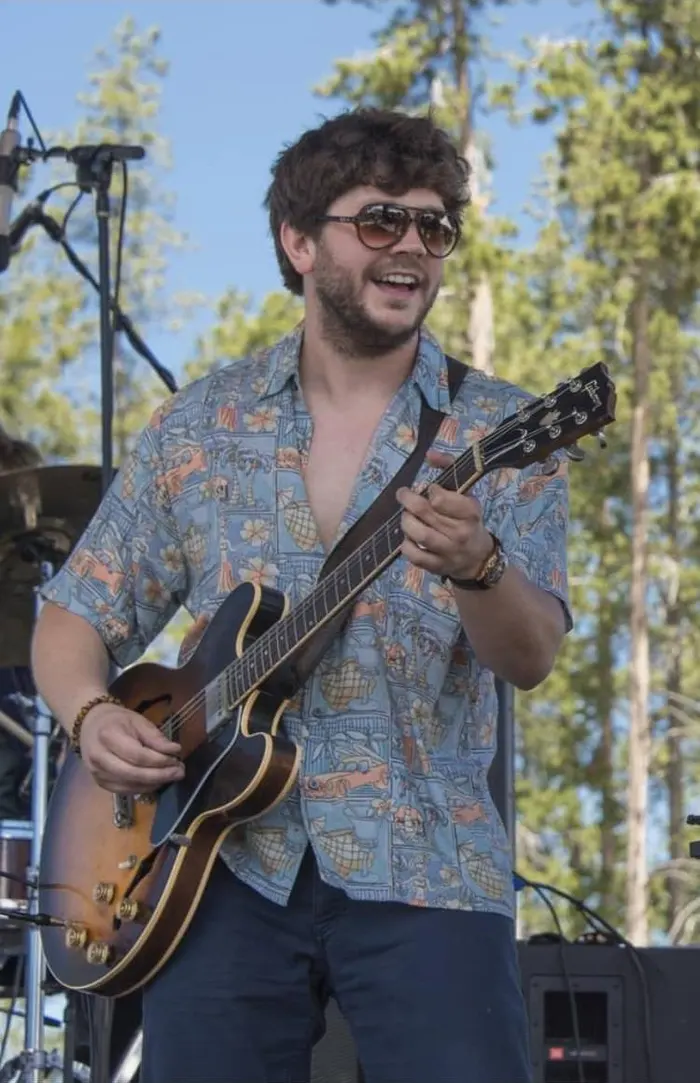 Johnny grinning mid-solo on an outdoor festival stage